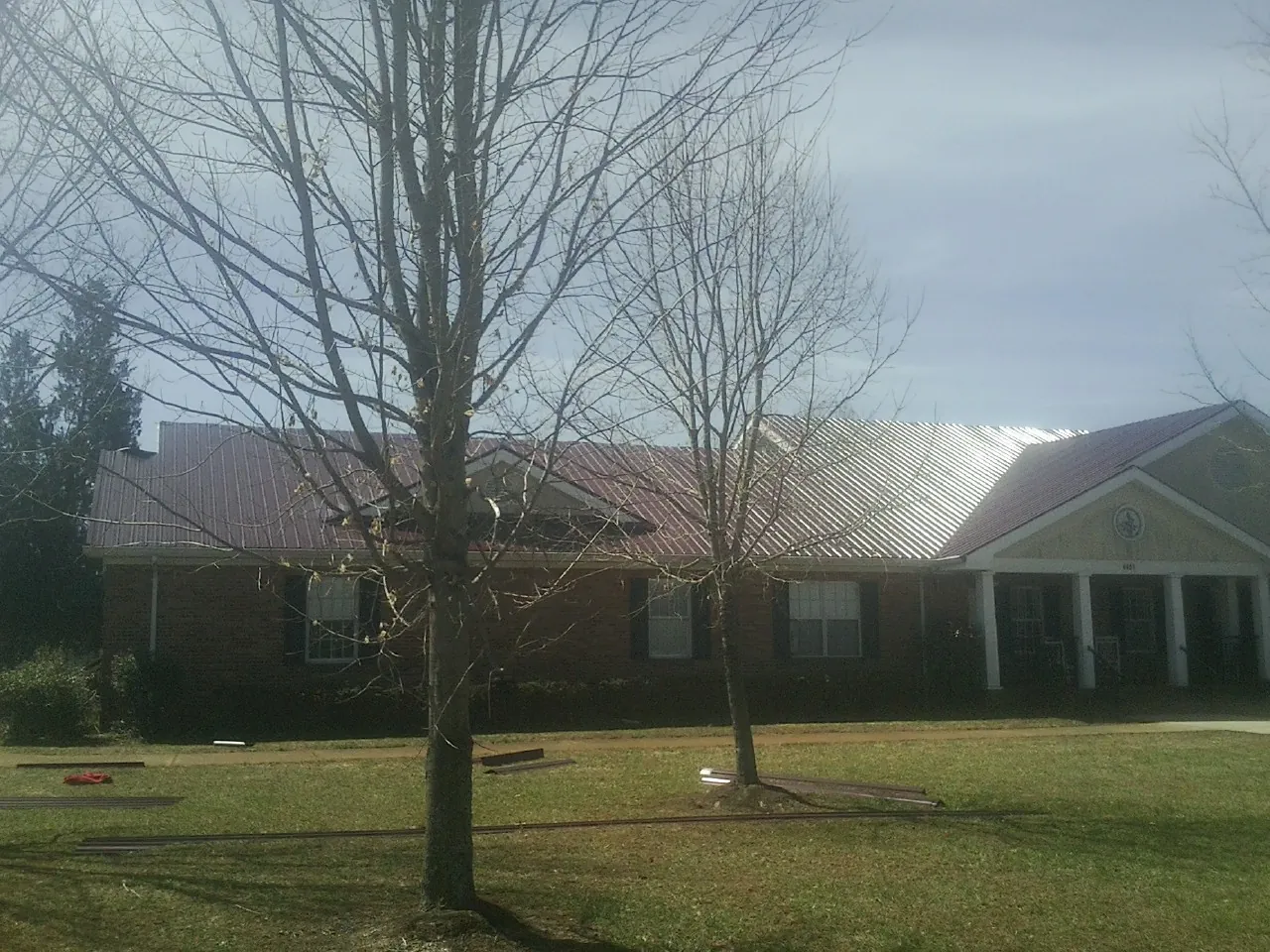 Red metal roof on a brick building seen from the front lawn in Holden