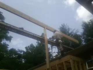 Carpenter setting a ridge beam over a new addition frame — Ice Dam Removal by Roofing Brothers in Holden