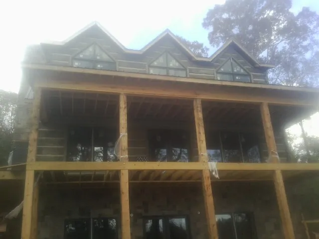 Dormers and porch framing on a large log home under construction — Roof Coating work by our crew in Holden