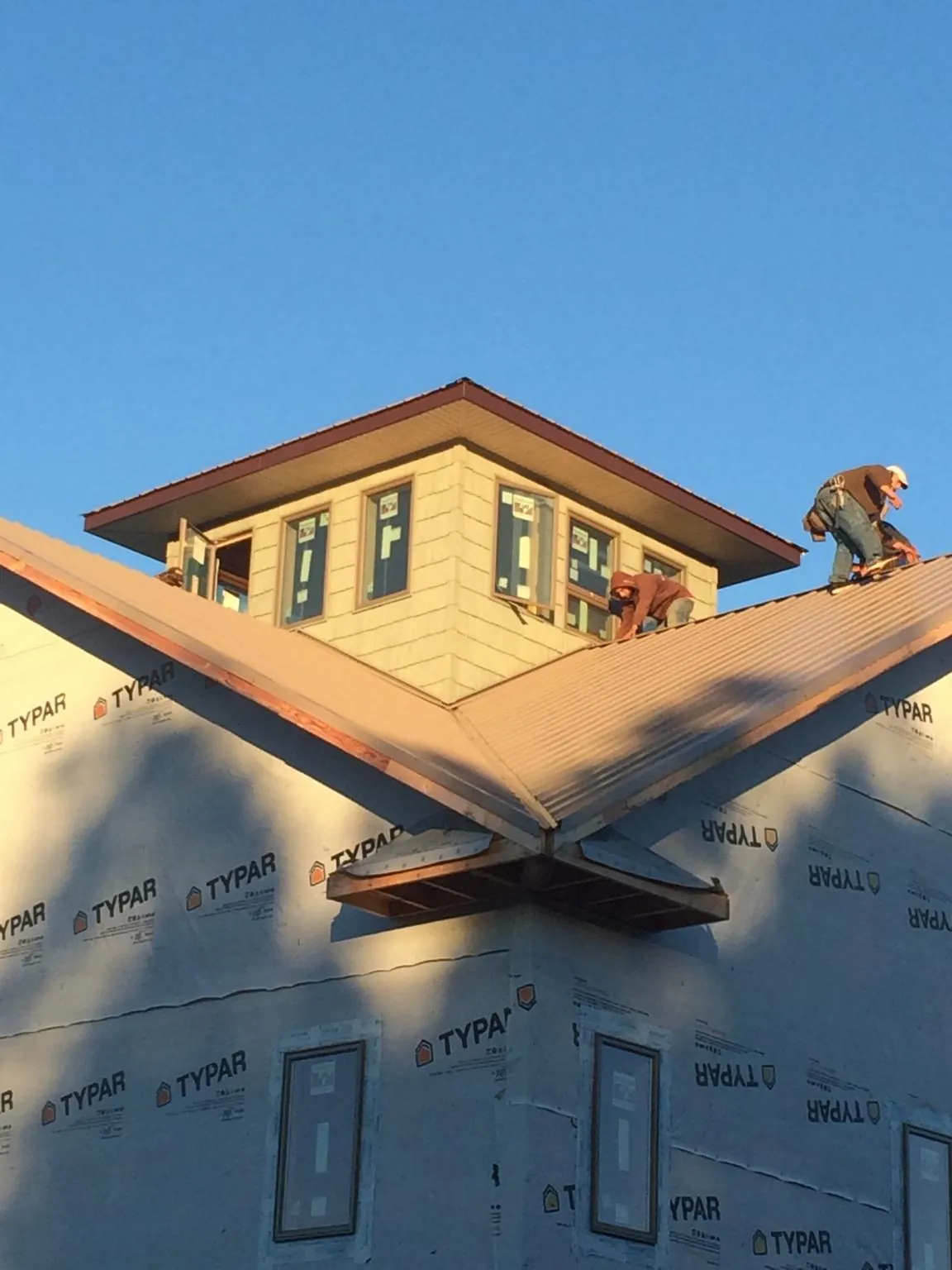 Roofers working around a rooftop cupola on a new metal roof at sunset — Roof Waterproofing in Holden by Roofing Brothers